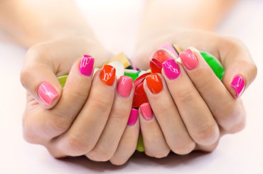 Multi-colored jelly sweets in the hands with a bright nail polish